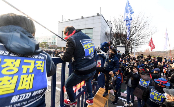 ▲ 금속노동조합 경남지부가 23일 한국지엠 창원공장 앞에서 한국지엠 비정규직 1교대 전환 반대 금속노동자 결의대회를 열었다. 대회에 참가한 노동자들이 공장 안에 있는 한국지엠 비정규직 노동자들과 함께하기 위해 굳게 닫힌 철문을 넘고 있다.  /박일호 기자 iris15@