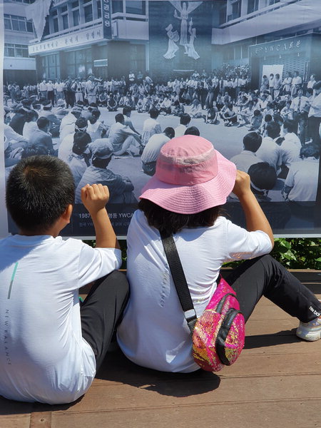 ▲ 정태완 씨 작품. 6월 민주항쟁 펼침막 앞에 앉아있는 아이들 뒷모습이 보인다.