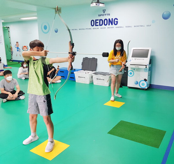 ▲ 김해외동초 학생들이 가상현실 스포츠실에서 양궁을 하는 모습./김해외동초