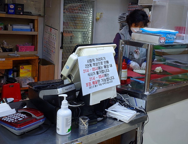 ▲ 한 분식집에서 자영업자가 김밥을 만들고 있다. 계산기 뒤에는 오후 9시 이후 포장만 가능하다는 안내 문구가 적혀 있다. /안지산 기자