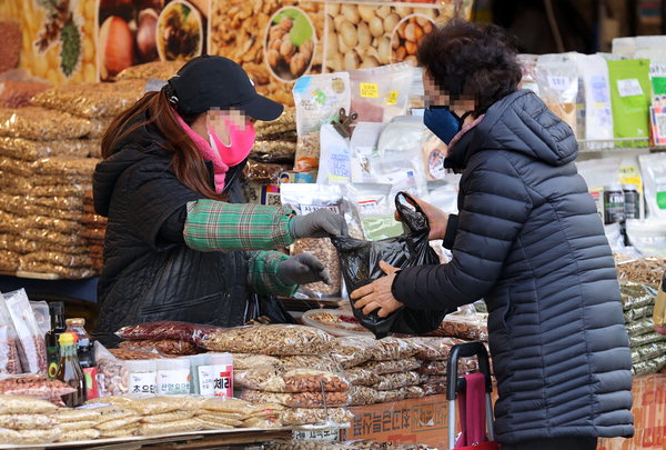 ▲ 대보름을 앞둔 24일 오전 한 전통시장에서 시민이 호두, 땅콩 등 부럼을 구매하고 있다. /연합뉴스