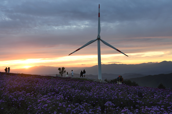 '감악산 꽃&별 여행'에 나선 이들이 해질무렵 풍력발전기를 배경으로 사진을 찍고 있다. /거창군