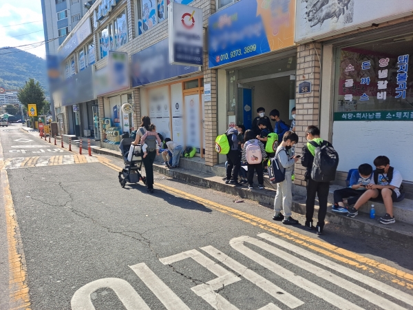 창원시 마산회원구 북성초등학교 후문 맞은편 학원 입구 앞에 아이들이 모여 앉아 학원 차량을 기다리고 있다. /박신 기자