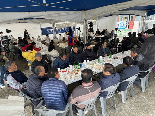 사단법인 국가무형 유산 남해안 별신굿 공개 행사 죽림마을 별신굿이 15일 거제시 거제면 죽림마을 회관 앞에서 열리고 있다. 굿판 한편에 음식과 술을 나누는 마을 주민들. /이서후 기자