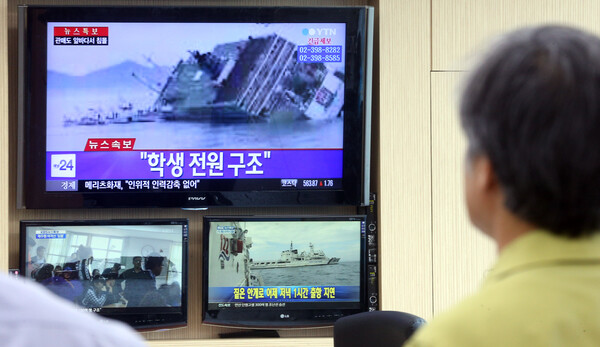 해양수산부 직원들이 2014년 4월 16일 오전 전남 진도 해상에서 발생한 세월호 참사 상황을 지켜보고 있다. 당시 뉴스에서 '학생 전원 구조'라는 오보가 흘러나오고 있다. /연합뉴스