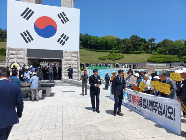3년 전 전 씨를 대신해 5.18 민주묘지에서 무릎을 꿇었던 합천 주민들이 18일 열린 정부 주관 5.18 기념식에 참여했다. 운동본부 회원들이 분향소 앞에서 펼침막을 들고 일해공원 이름 바꾸기 운동에 동참할 것을 호소하고 있다. /'생명의 숲 되찾기 합천군민 운동본부'