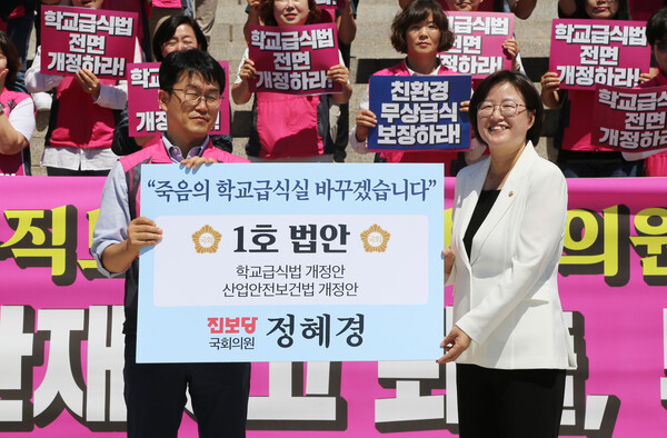 정헤경(오른쪽) 진보당 국회의원이 국회 본관 앞 계단에서 열린 '학교급식실 산업재해 퇴출, 부실 급식 퇴출법' 통과 촉구 기자회견에서 1호 법안 내용이 담긴 팻말을 들어보이고 있다. /진보당