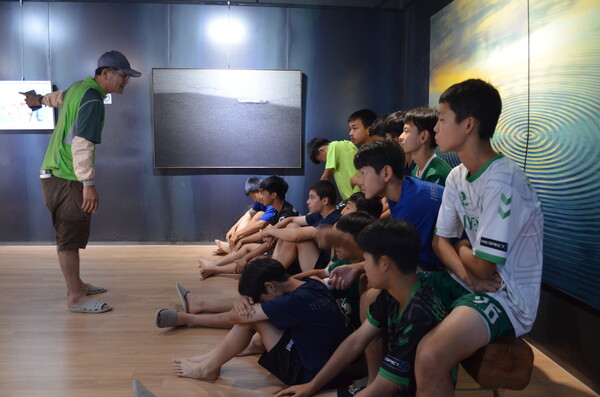 창녕 성산중학교 2학년 학생들이 모내기 체험에 앞서 우포늪 인근 정봉채갤러리에서 따오기 사진 등을 놓고 이야기를 나누고 있다. /이동욱 기자