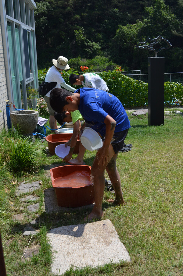 창녕 성산중학교 2학년 학생들이 우포늪 인근 정봉채갤러리 앞 논에서 모내기를 하고 손발과 옷에 묻은 진흙을 씻어내고 있다. /이동욱 기자