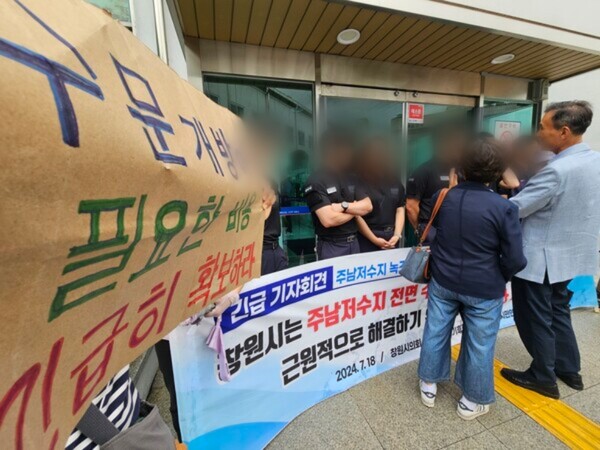 시민사회단체들이 비가 내린 18일 오후 기자회견을 마치고 나서 홍남표 창원시장에게 회견문을 전달하려고 시청 본관 진입을 시도하고 있다. 청원경찰들이 입구를 막아 결국 건물 안에 들어가지 못했다. /최석환 기자