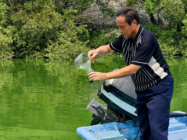 박창근 대한하천학회장(가톨릭관동대 토목공학과 교수)이 19일 오전 국립환경과학원 매리수질측정센터(김해 상동면 매리)과 2km 떨어진 매리1교 다리 밑 낙동강변에서 뜬 녹조물을 유리병에 담고 있다. /최석환 기자