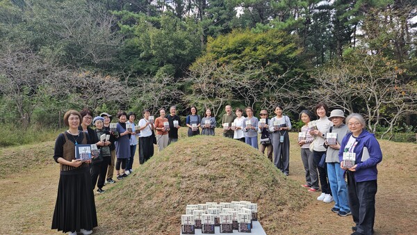일본어판 〈토지〉 20권 완역을 기념해 통영을 찾은 쿠온출판사 김승복 대표와 번역가·일본인 독자 30여 명이 산양읍 박경리 선생 묘소를 찾아 책을 헌정하고 있다.  왼쪽 첫번 째가 시미즈 지사코 번역가, 그 옆이 김승복 대표. /정봉화 기자 