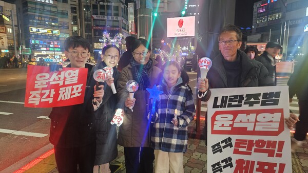 지난 10일 통영 북신동에서 열린 윤석열퇴진 촉구 촛불대회에 참가한 박종숙ㆍ최순자 씨 가족과 이웃 꼬마(가운데)가 함께 기념사진을 찍고 있다. /정봉화 기자