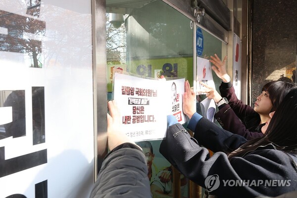 더불어민주당 경남도당 청년위원회 관계자들이 11일 오후 경남 창원시 국민의힘 경남도당 당사 건물 출입문 앞에 국민의힘 의원들의 대통령 탄핵 표결 불참에 항의하는 문구가 적힌 피켓을 부착하고 있다. /연합뉴스