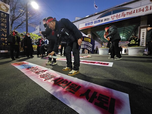 13일 오후 5시 30분께 창원시의회 앞에서 노동계 인사들이 의회 입구 앞 바닥에 래커칠을 하고 있다. /최석환 기자