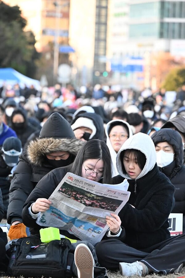 집회에 참가한 시민들이 현장에 배포된 경남도민일보 신문을 읽고 있다.  /김구연 기자