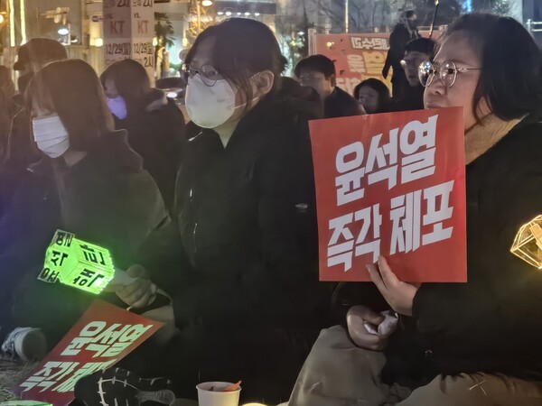 24일 오후 윤석열 대통령 탄핵 촉구 집회를 찾은 시민들이 손펫말과 야광봉을 들고 바닥에 앉아있다./최석환 기자