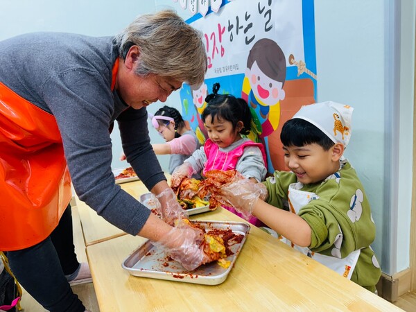 어린이집 김장 행사에 참가한 한 할머니가 아이들과 김치를 만들고 있다. /박영희