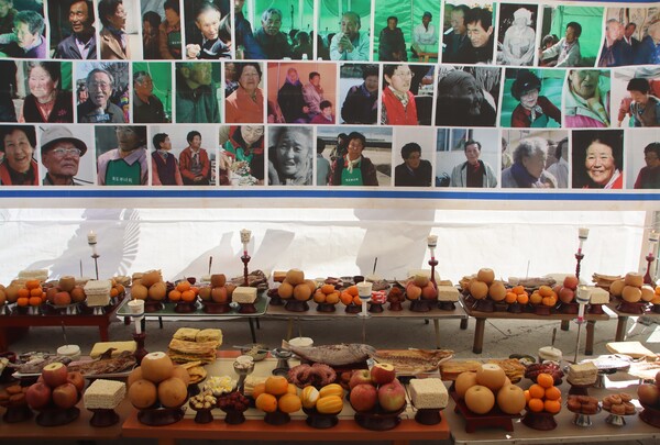 본당에 차려진 거리 밥상. 원래는 자식이 나이든 부모에게 바치는 상이지만, 이젠 죽은 이들의 넋을 기리는 의미로 차려지고 있다. 사진 속 대부분은 세상을 떠났다. /백솔빈 기자