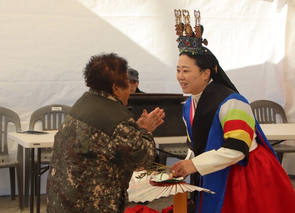 마을 어르신이 무당에게 상전(상돈)을 바치며 인사하고 있다. /백솔빈 기자