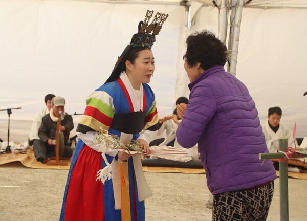 마을 어르신이 무당에게 상전(상돈)을 바치며 인사하고 있다. /백솔빈 기자