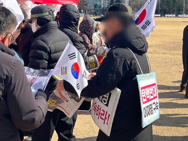 23일 창원시청 광장에서 열린 대통령 탄핵 반대 집회에서 한 시민이 자유일보를 집회 참가자들에게 나눠주고 있다. /김다솜 기자 
