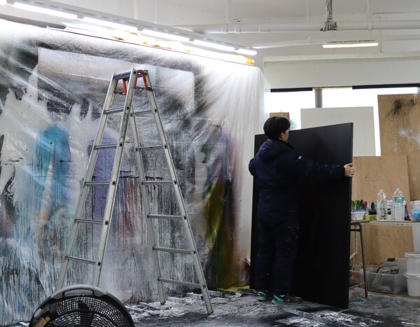 작업복을 입은 김성훈 작가가 작품을 옮기고 있다. /백솔빈 기자