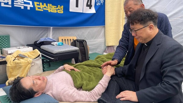 백남해 천주교 마산교구 신부가 22일 오후 윤석열 대통령 탄핵 촉구 단식 농성 14일 차를 보내고 있는 김경수 전 경남도지사를 찾아 위문하고 있다. 김 전 지사는 이 만남 이후 이날 오후 7시 15분께 병원으로 이송됐다. /김경수 전 경남지사 공보방