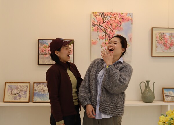 진해 벚꽃을 그리는 편지현(왼쪽) 작가와 박기정 도자랑 대표가 서로 마주보며 웃고 있다. /백솔빈 기자