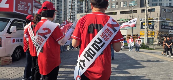 국민의힘 선거운동원들은 후보 이름이 적히지 않은 옷을 입고 선거 유세에 나섰다. 대신 어깨띠로 후보 이름을 알렸다. /안지산 기자 