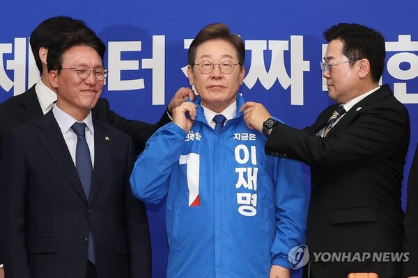 더불어민주당 박찬대 당대표 직무대행 겸 원내대표가 지난달 28일 서울 여의도 국회에서 열린 최고위원회의에서 이재명 대선 후보에게 선거운동용 파란색 점퍼를 입혀주고 있다. /연합뉴스 