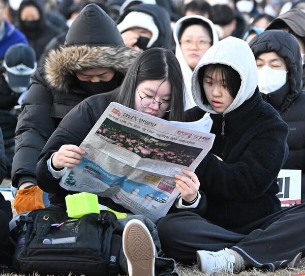 2024년 12월 14일 윤석열 대통령 탄핵소추안 국회 통과 촉구 집회에 참가한 시민들이 현장에 배포된 경남도민일보 신문을 읽고 있다. /김구연 기자 sajin@idomin.com