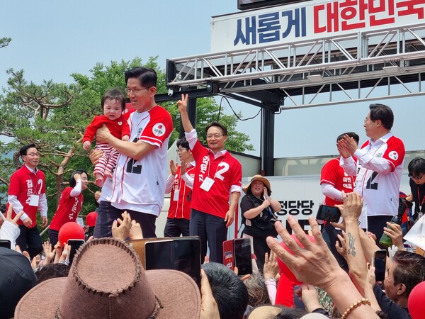 국민의힘 김문수 대선 후보가 28일 낮 12시 김해 수로왕릉 앞에서 어린 아이를 안고 유세 연단에 올라가는 퍼포먼스를 하고 있다. /이수경 기자