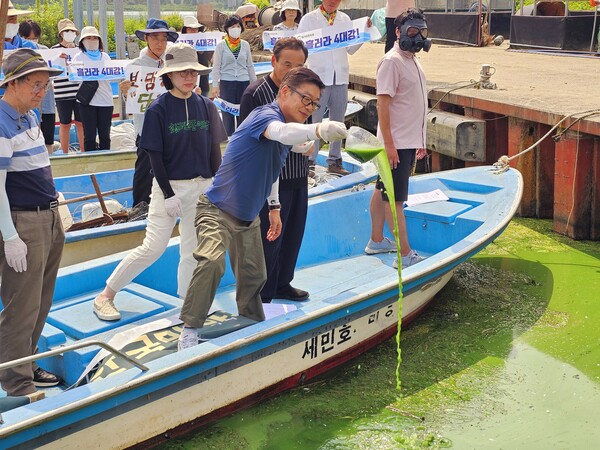 강호열 낙동강네트워크 공동대표가 김해 대동면 초정리 대동선착장에서 녹조물을 강에 붓고 있다. /경남도민일보DB