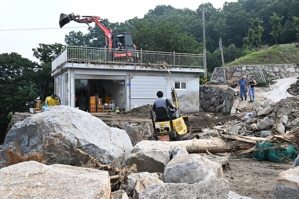 산청군 산청읍 모고마을 폭우 피해현장에서 23일 굴삭기가 집 옥상에 올리가 떠내려온 돌을 치우고 있다./김구연 기자