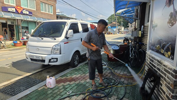 의령군 대의면 구성마을에서 식당을 하는 주민이 23일 오전 고압 양수기를 이용해 침수된 집기를 씻고 있다.  /유은상 기자