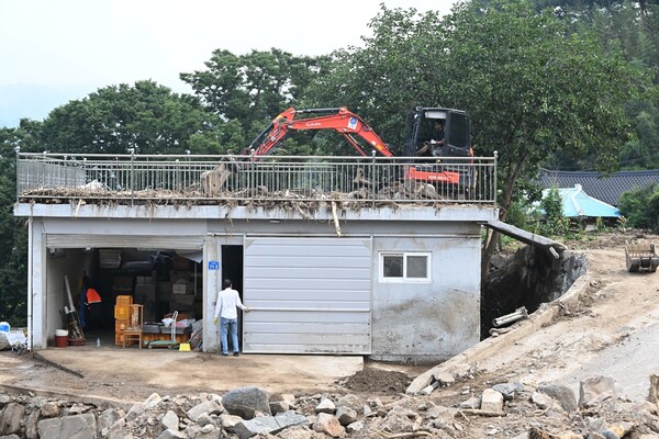 산청군 산청읍 모고마을 폭우 피해현장에서 23일 굴삭기가 집 옥상에 올리가 떠내려온 돌을 치우고 있다./김구연 기자