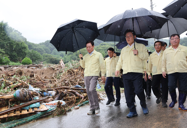 이재명 대통령과 박완수 경남도지사 등이 21일 집중호우로 산사태가 발생한 산청군 산청읍 부리마을에서 비가 내리는 가운데 피해 상황을 점검하고 있다. /연합뉴스