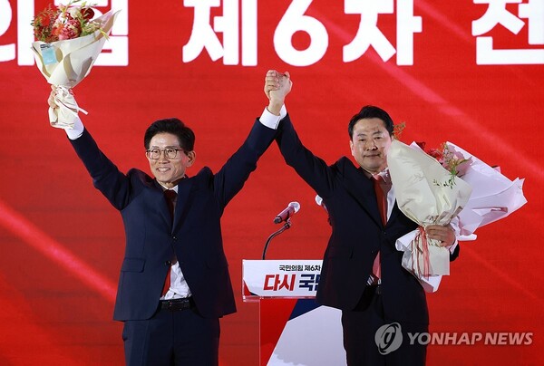22일 충북 청주시 흥덕구 청주오스코에서 열린 국민의힘 제6차 전당대회에서 결선에 진출한 김문수, 장동혁 당대표 후보가 꽃다발을 받은 뒤 맞잡은 손을 들어 올리고 있다. /연합뉴스