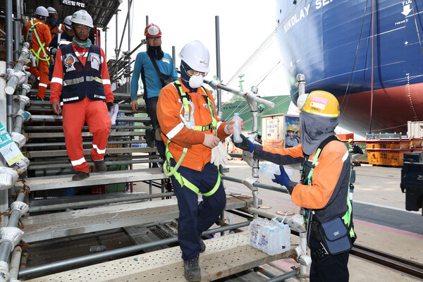 한화오션 안전관리자가 오후 쉬는 시간 휴식을 위해 하선하는 작업자들에게 얼음 생수를 전달하고 있다./한화오션