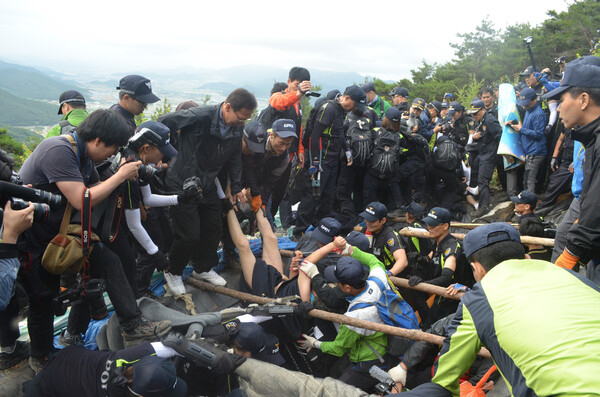 경찰이 2014년 6월 11일 밀양 송전탑 공사를 반대하는 129번 움막을 철거하고 있다. 129번 움막에서 알몸인 주민들을 끌어내고 있다. /경남도민일보DB