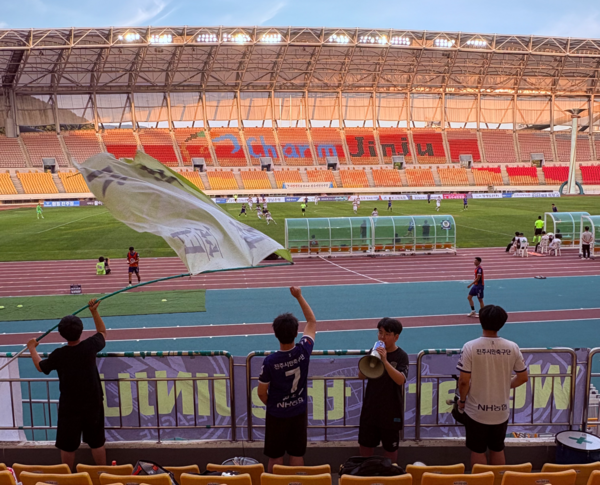 진주시민축구단 서포터스남강전사 회원들이 응원을 펼치고 있다. 류현준(오른쪽 둘째) 대표가 확성기에 대고 구호를 외치고 있다. /류현준