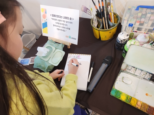 진주 아트숲나래미술 제3회 전시회 <나를 만나는 여행>이 25일까지 진주문화제작소에서 열린다. 한 관람객이 방명록을 작성하고 있다. /류민기 기자